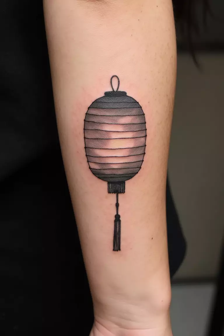 A close up shot of woman's arm with a black ink simple Japanese lantern design tattoo  