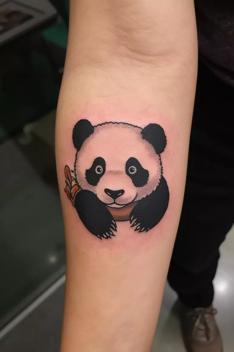A close up shot of woman with a single needle baby panda tattoo on her forearm.  