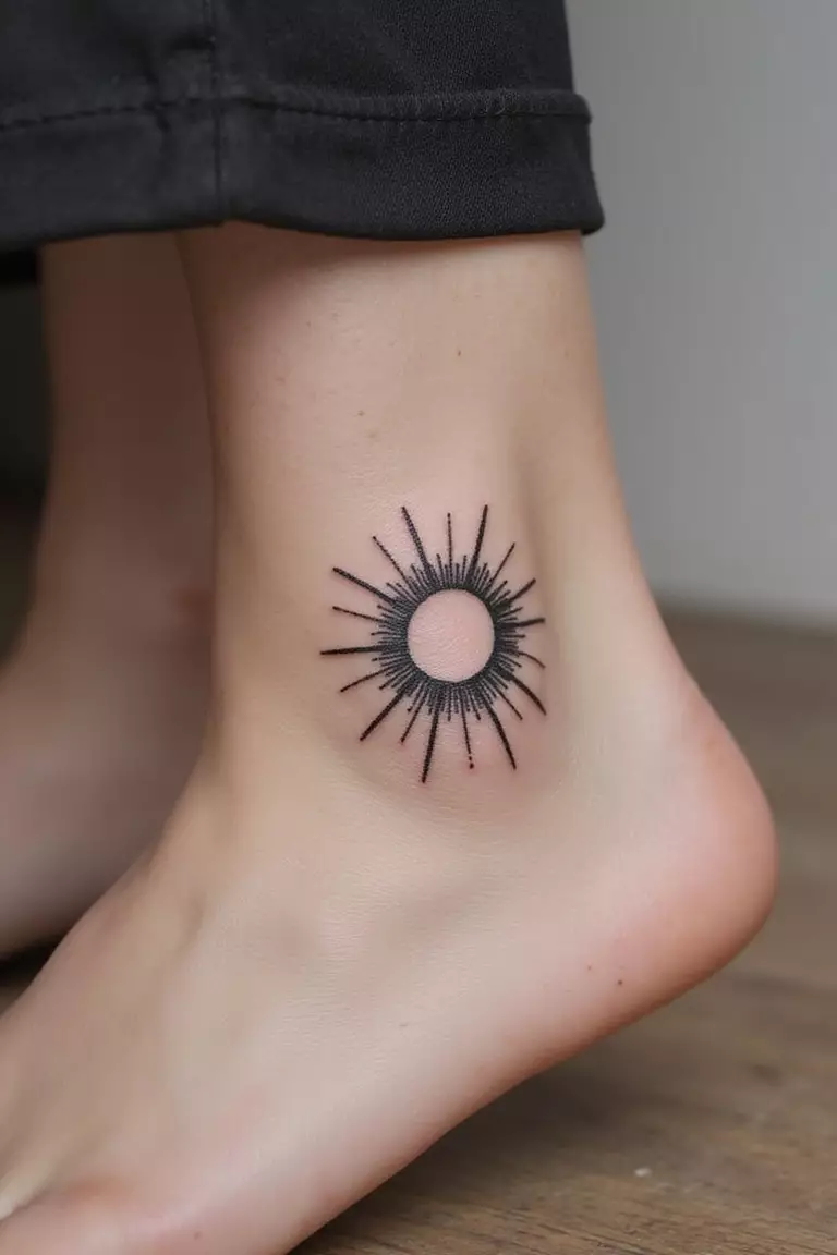 A close-up shot of a woman showing her black ink minimalist sun with rays tattoo design on her ankle