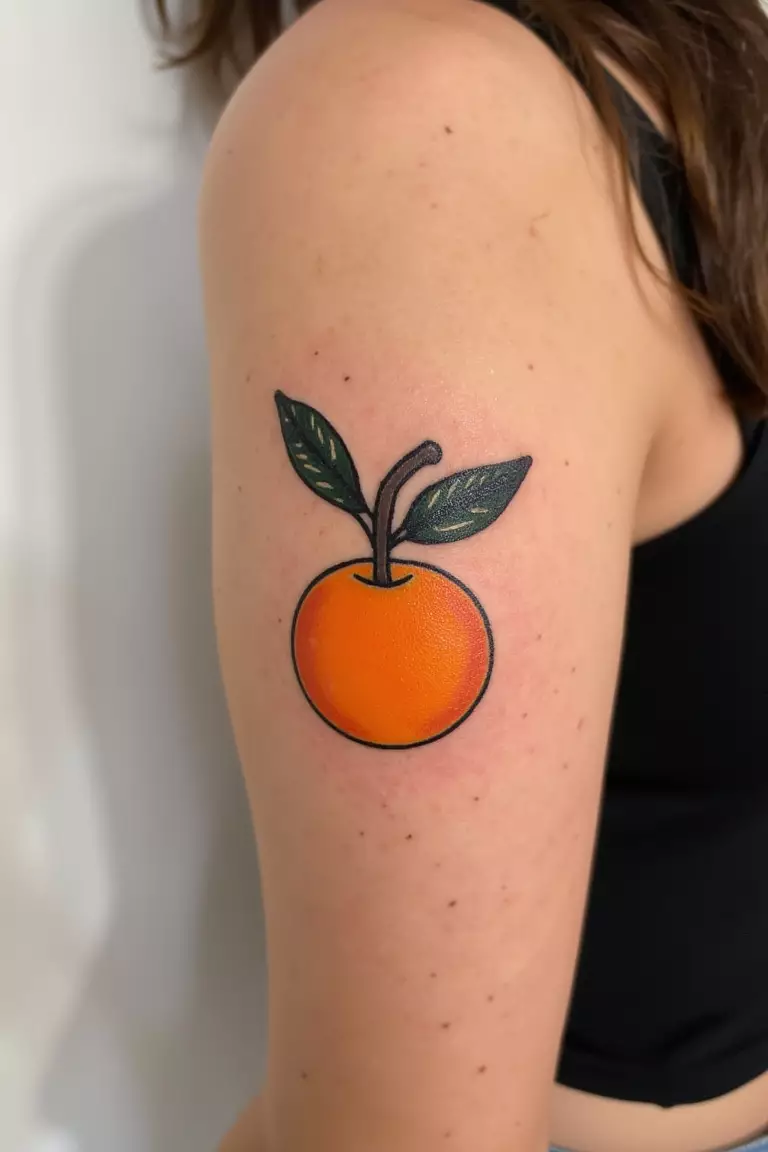 A close up shot of woman's arm with a black ink tattoo featuring a bold, bright orange fruit design, unexpected and delightfully summery.