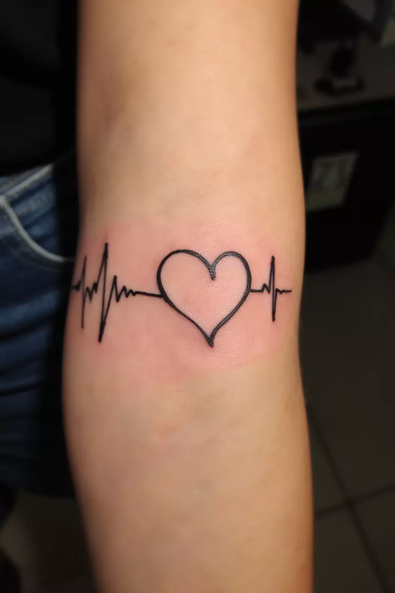 A close up shot of woman's arm with a black ink heartbeat line tattoo, EKG rhythm forming heart shape