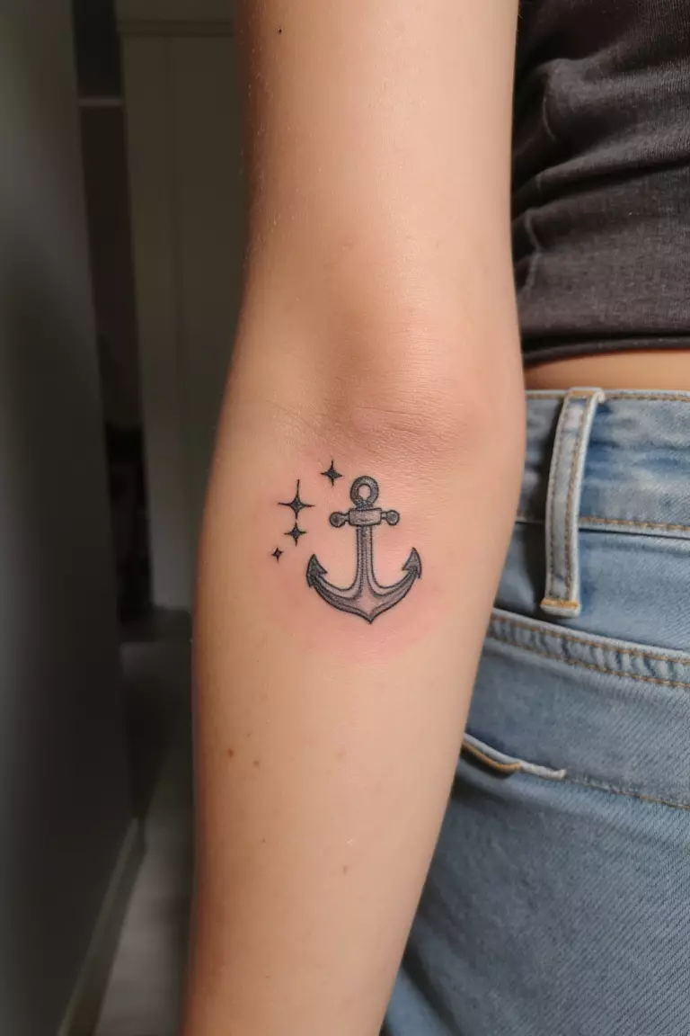 Minimal Anchor with Stars A close up shot of woman's arm with a black ink minimal anchor with stars tattoo.