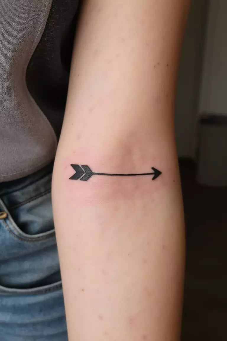 A close up shot of woman's arm with a black ink single arrow tattoo, simple and elegant design, clean lines