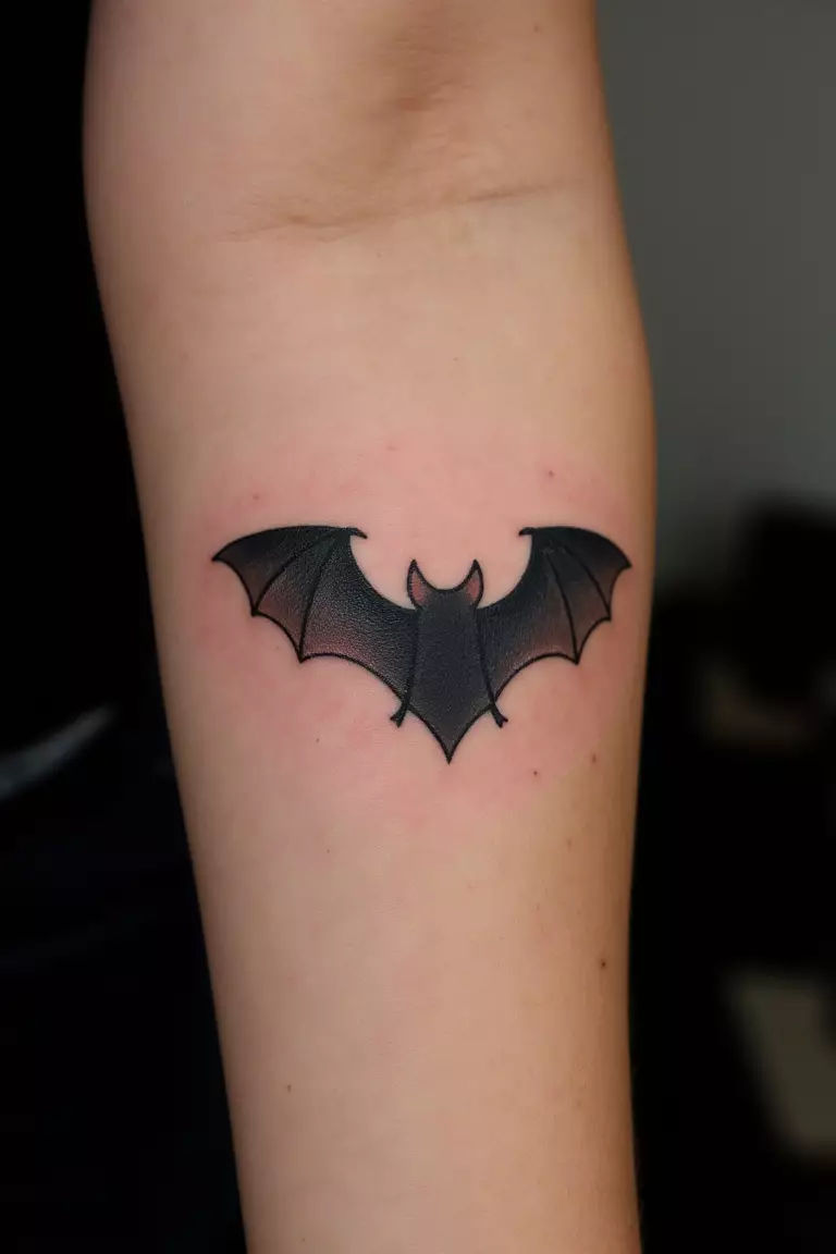 A close up shot of woman's arm with a black ink tattoo of a realistic bat.