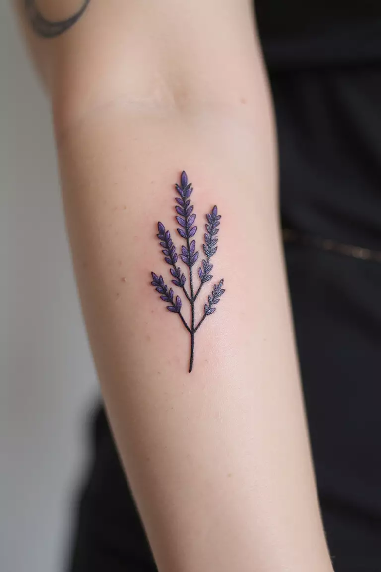 A close up shot of woman's arm with a black ink tattoo of a simple lavender sprig silhouette.