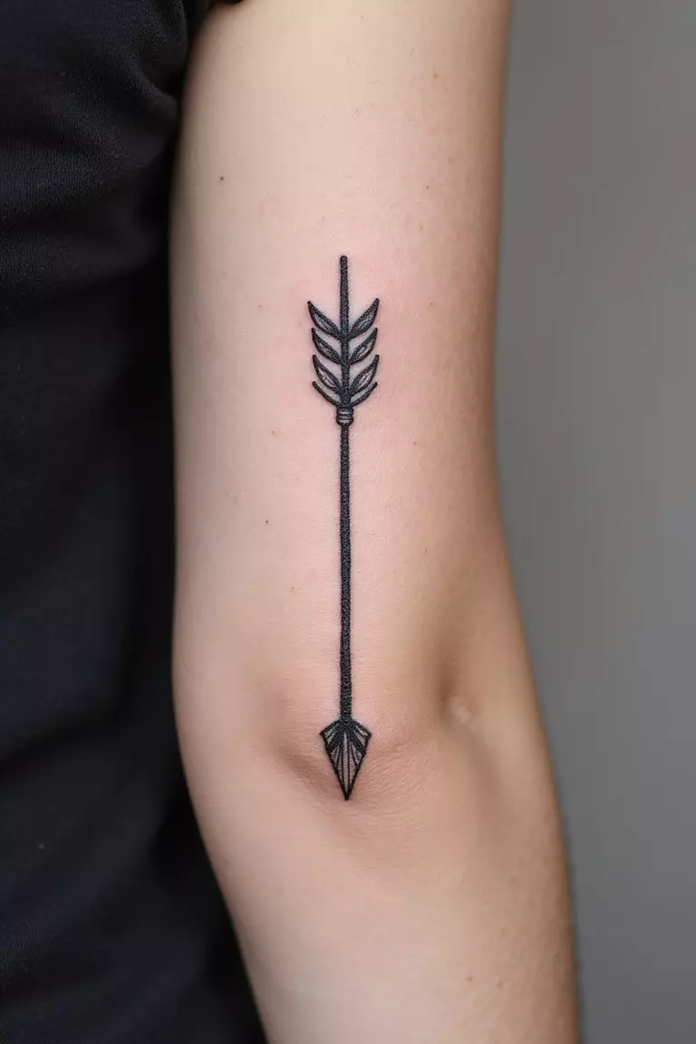 Arrow A close-up shot of a woman's arm with a black ink tattoo of a single, detailed arrow with simple fletching.