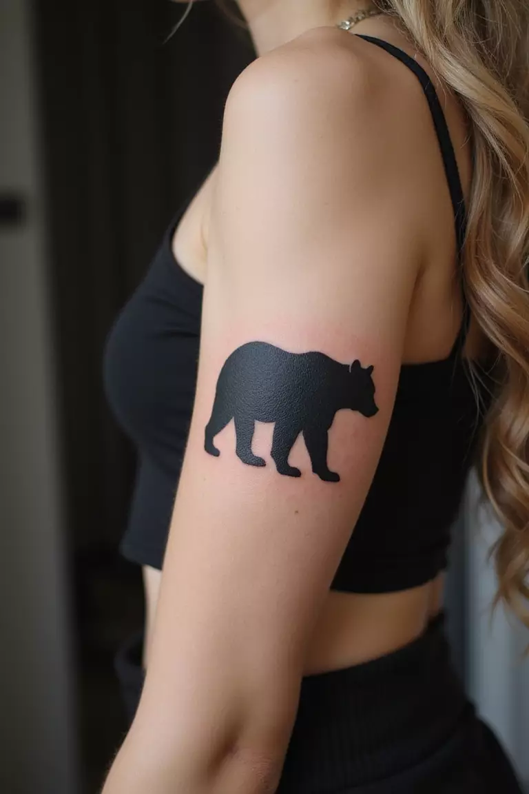 Bear Silhouette A close-up shot of a woman showing her black ink bear silhouette tattoo on her arm.