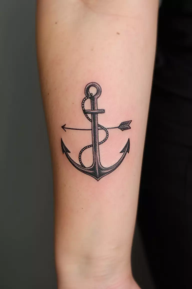 A close up shot of woman's arm with a black ink arrow and anchor tattoo, symbols combined to represent stability and direction
