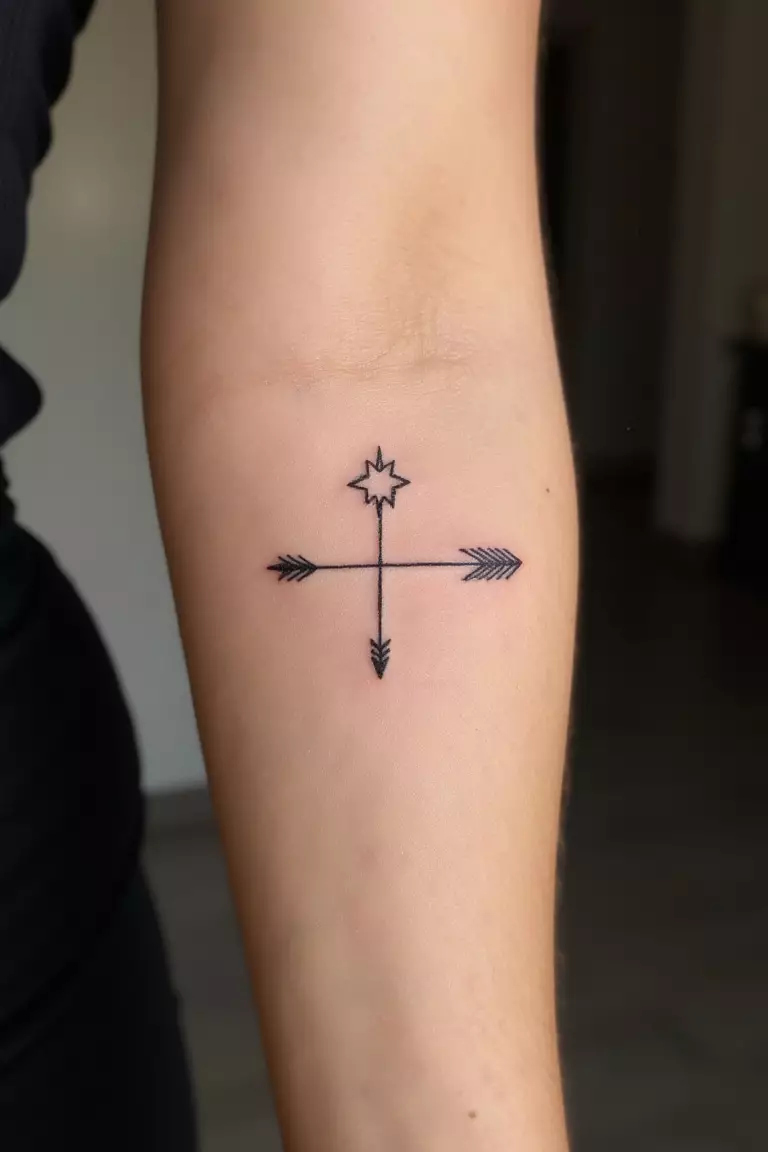 A close up shot of woman's arm with a black ink arrow and star tattoo, arrow pointing toward a star design