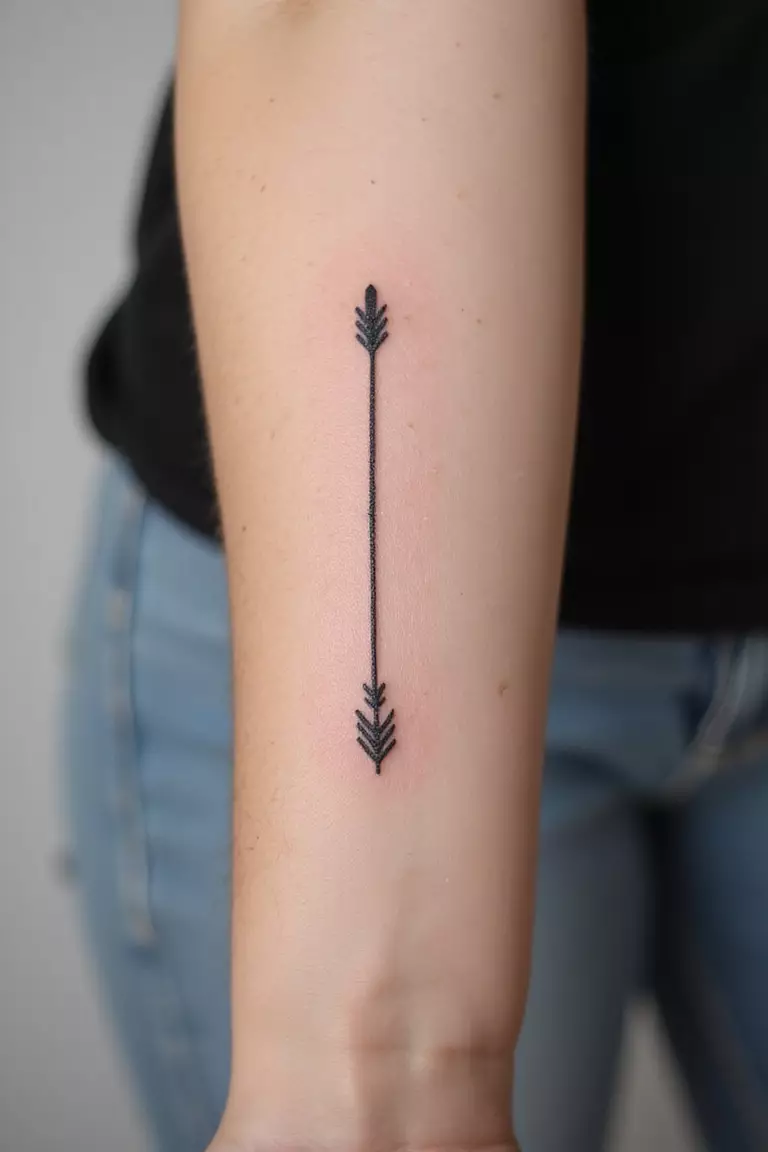 A close-up shot of a woman showing her black ink minimalist single arrow tattoo design on her forearm