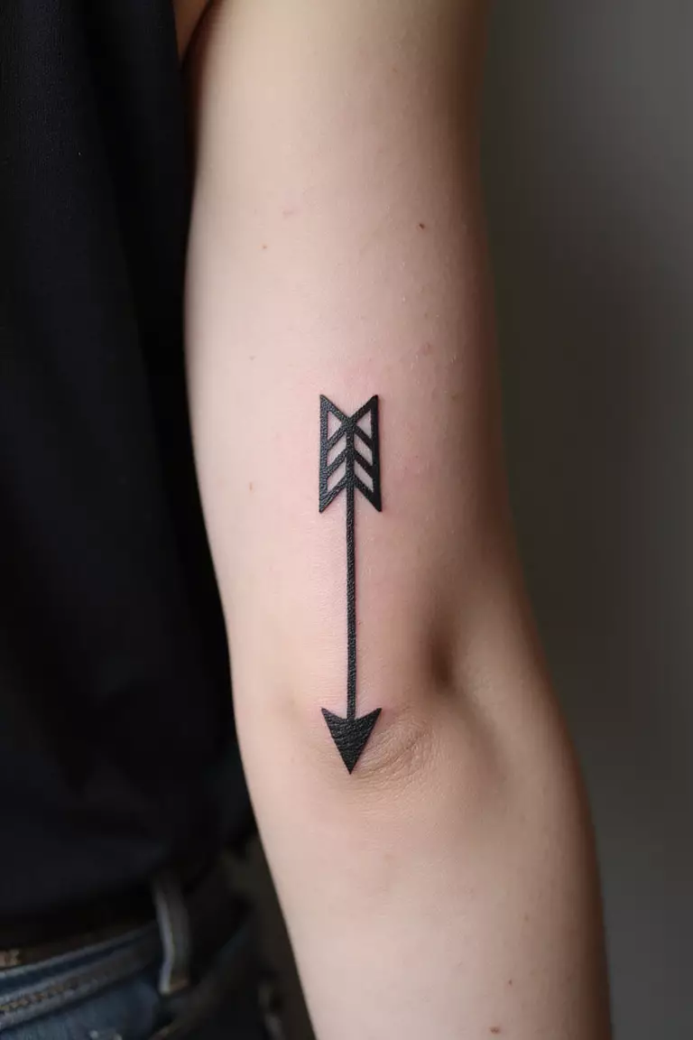 A close-up shot of a woman showing her black ink single bold arrow tattoo on her arm