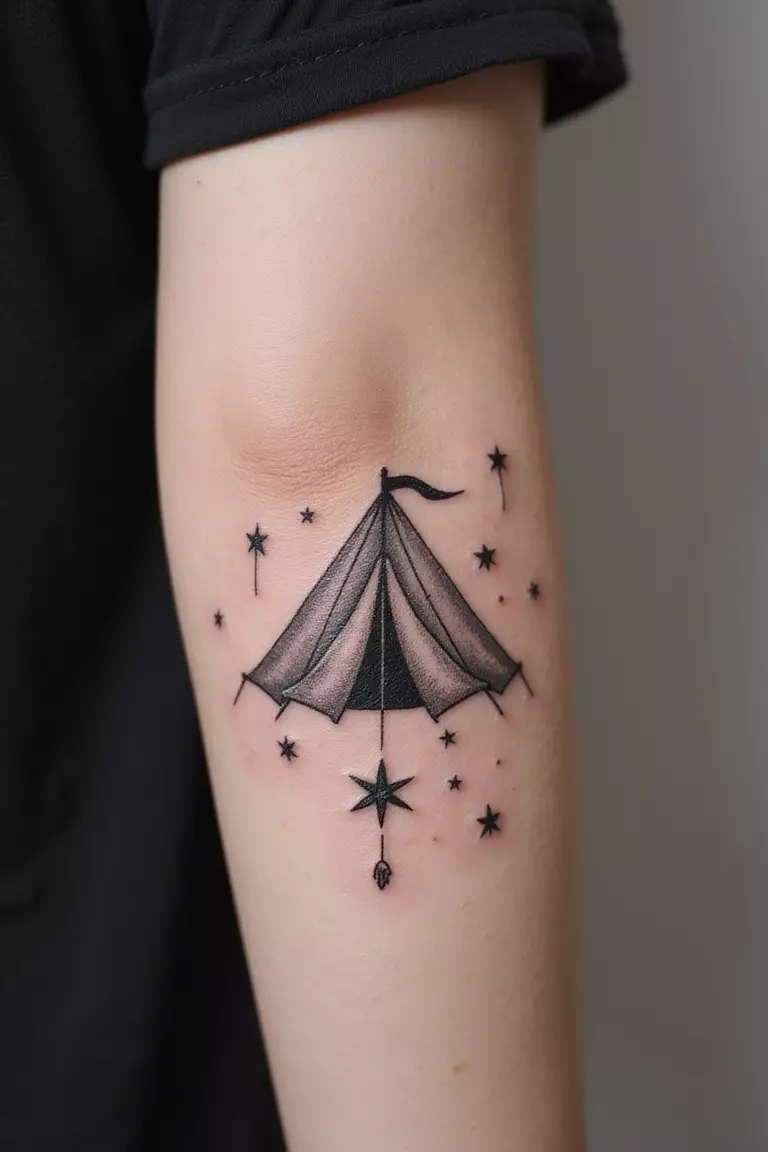 A close-up shot of a woman showing her black ink tent under stars tattoo design on her arm