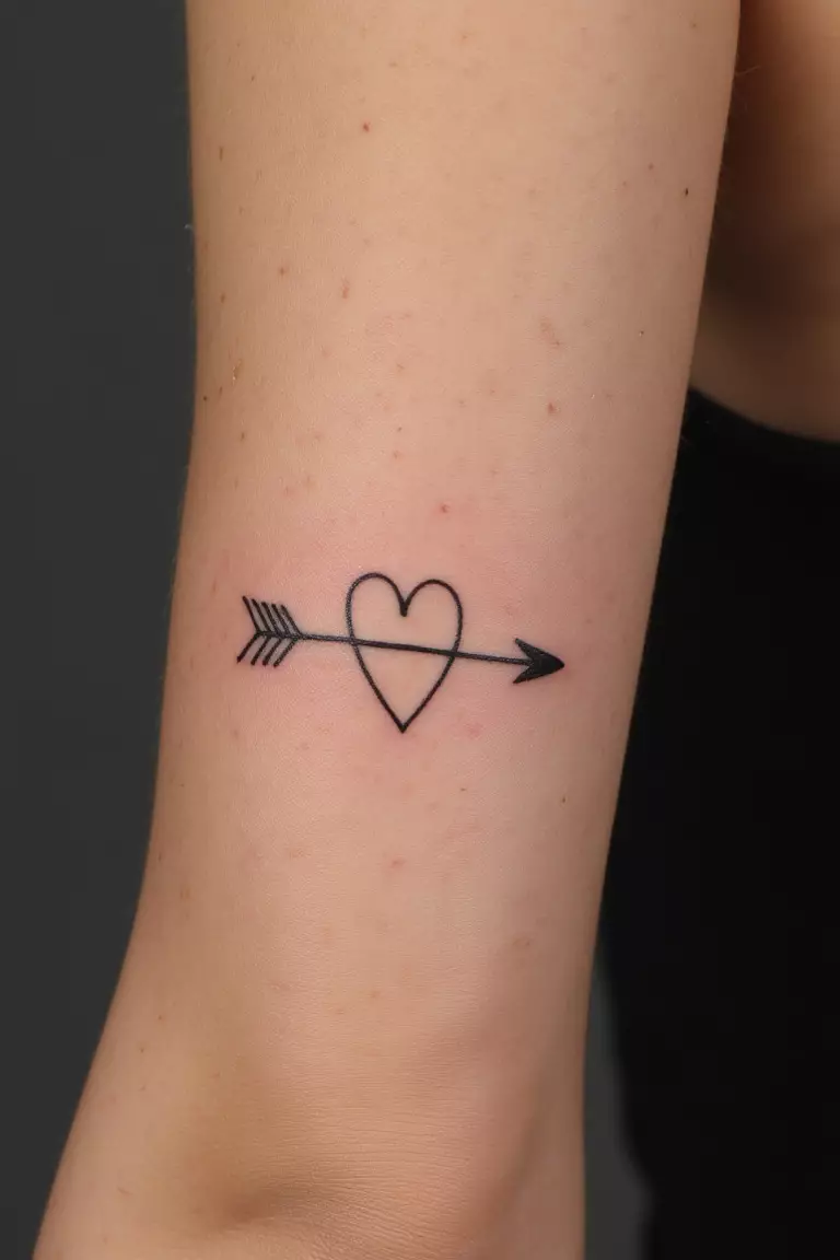 A close up shot of woman's arm with a black ink arrow with heart tattoo, arrow piercing through a small heart