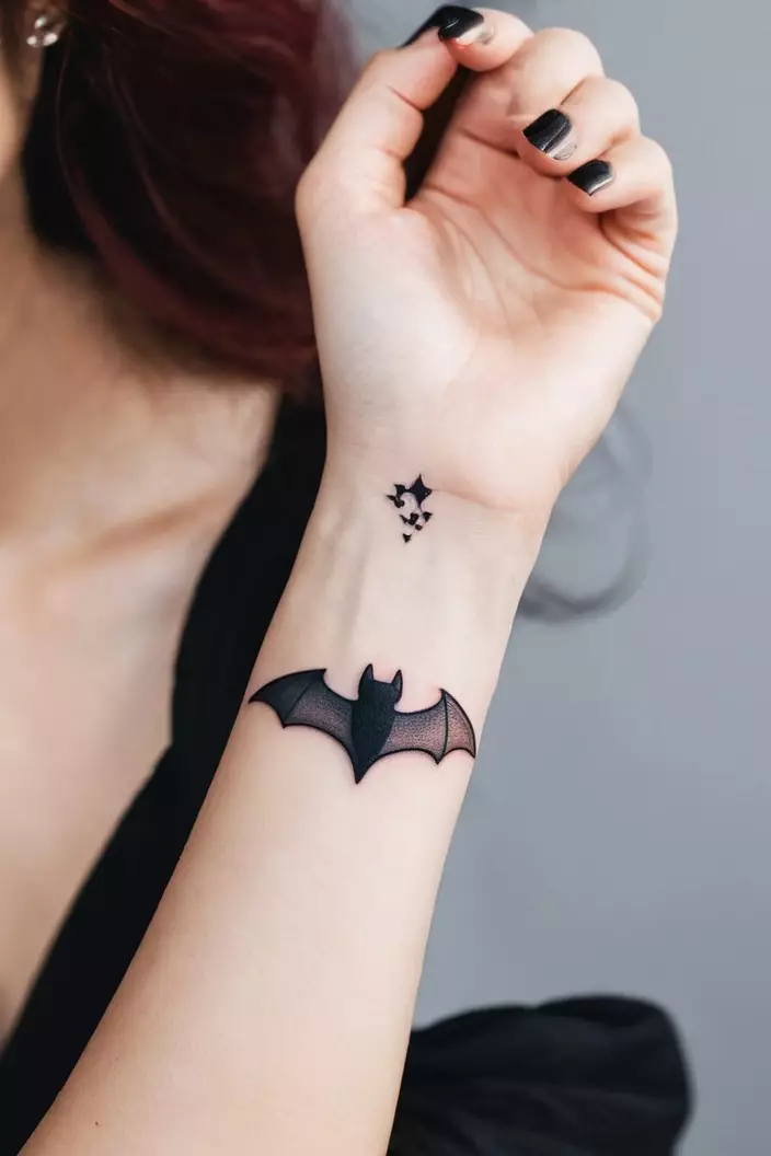 A close-up photo of a woman showing her cute minimal bat tattoo on her wrist, with simple outlines and a charming design.  
