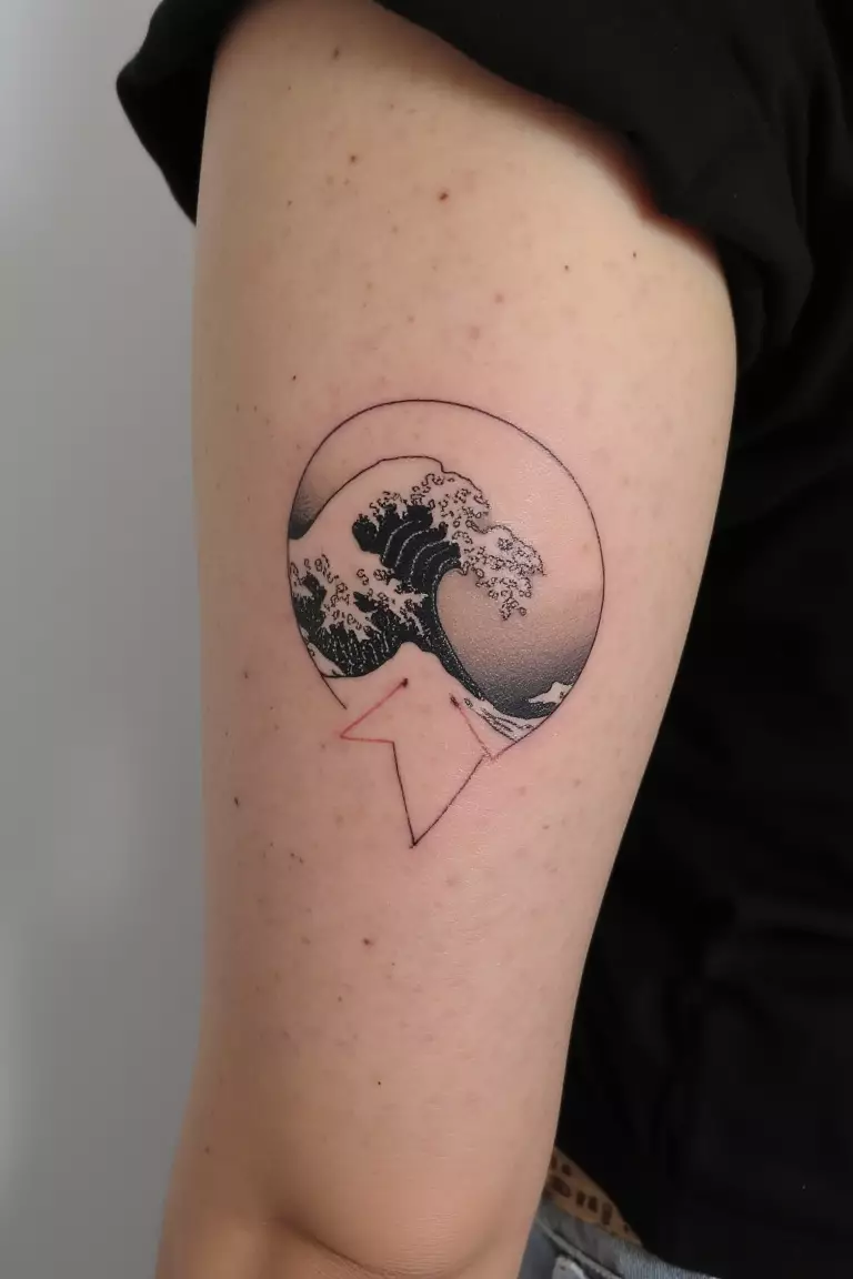 A close up shot of woman's arm with a black ink minimalist wave pattern inspired by Hokusai tattoo  